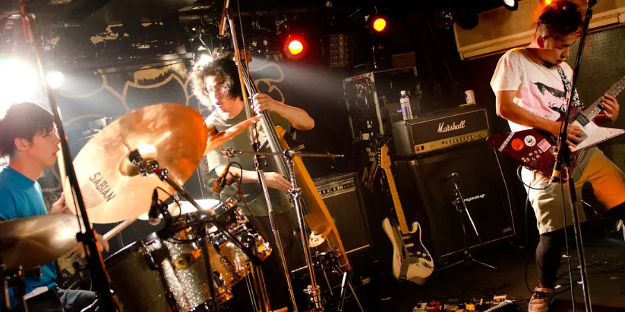 A band performs in an enclosed live music venue in Koenji