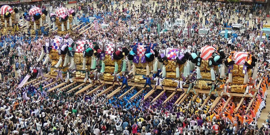 Elaborately decorated taiko drum floats carried through a large crowd at the Niihama Taiko Matsuri in Japan