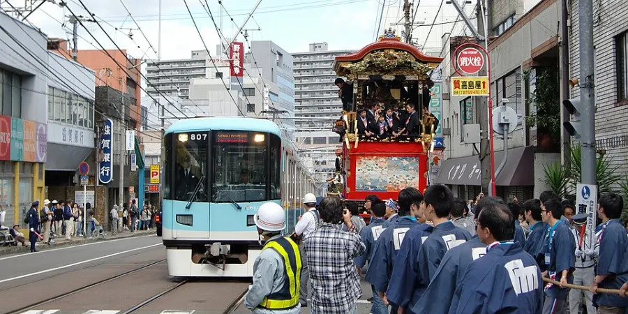 Traditional Otsu Matsuri festival float passing a streetcar through the streets of Otsu, Japan