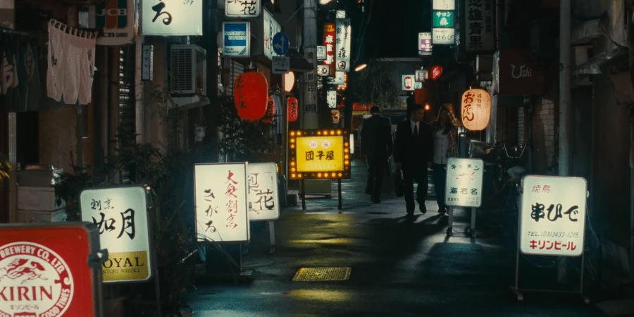 Shohei Sugiyama (Kōji Yakusho), alone in his dark suit, walking through the brightly lit streets of Tokyo at night, symbolizing his quiet defiance of typical salaryman drinking culture.