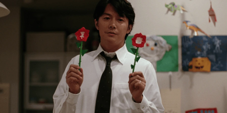 A Salaryman holds two paper flowers, as to symbolize a brighter future.