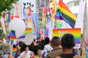 busy street in shinjuku nichome tokyo filled with rainbow flags and crowd celebrating lgbtq pride festival.