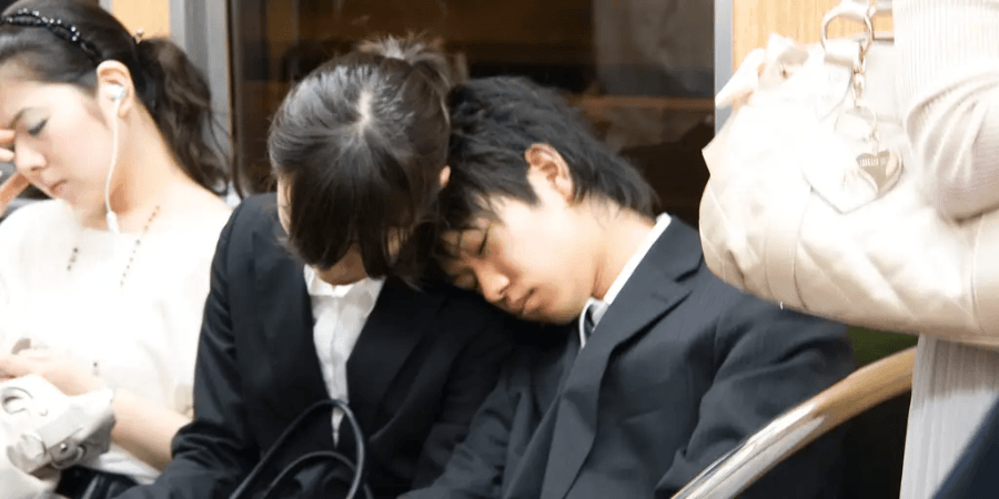 Japanese workers sleeping on the metro due to exhaustion from overworking.