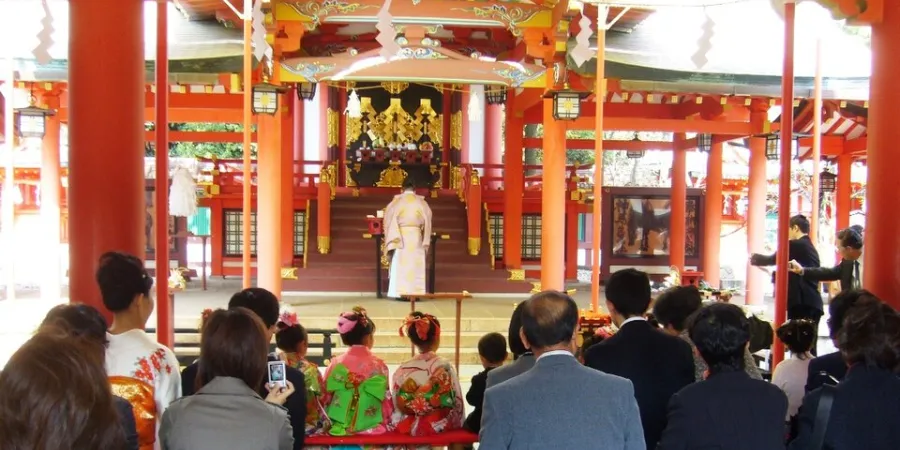 Families attending a Shichi-Go-San ceremony at a colorful Japanese shrine with children dressed in traditional clothing