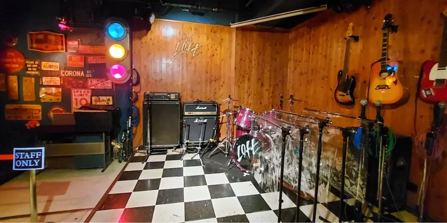 Interior of Loft, with guitars hanging on the walls. Drums and other instruments are laid out.