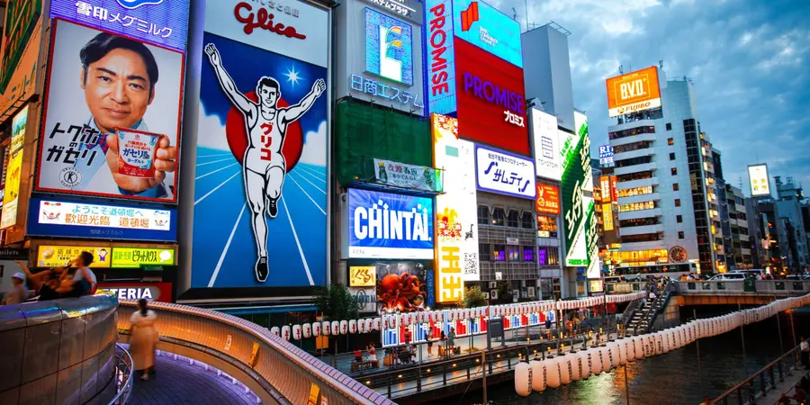 A landscape image of Dotonbori with neon lights and billboards