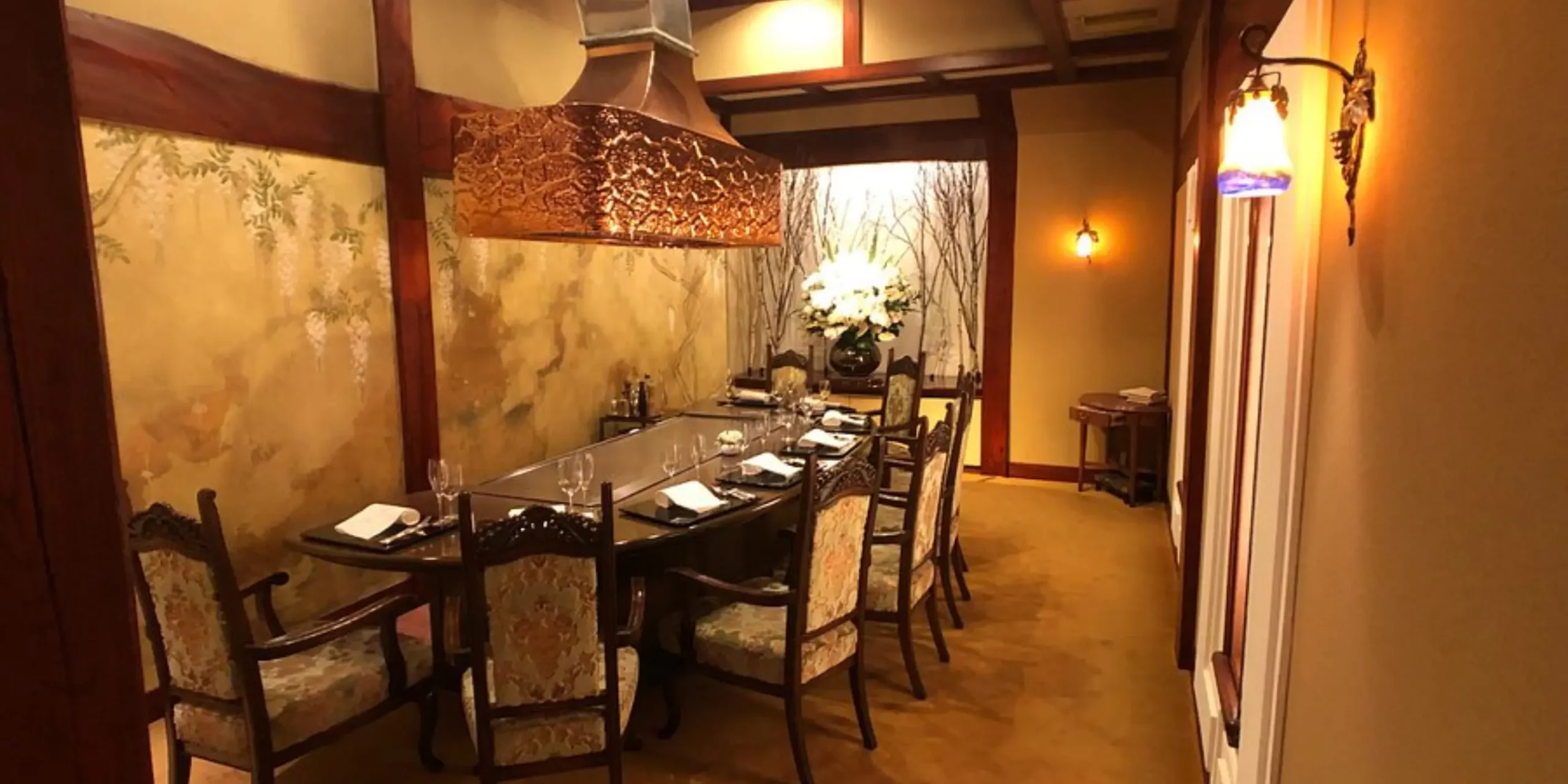 Private dining room at Ginza Ukai-Tei, with a teppanyaki grill table, ornate chairs, and warm lighting beneath a decorative copper hood