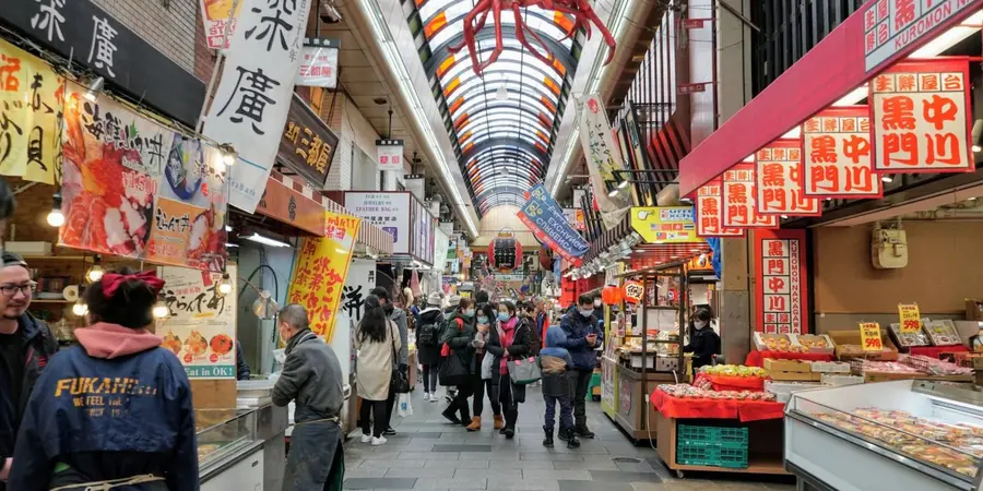 A landscape image of Kuromon Ichiba Market with vendors on the sides