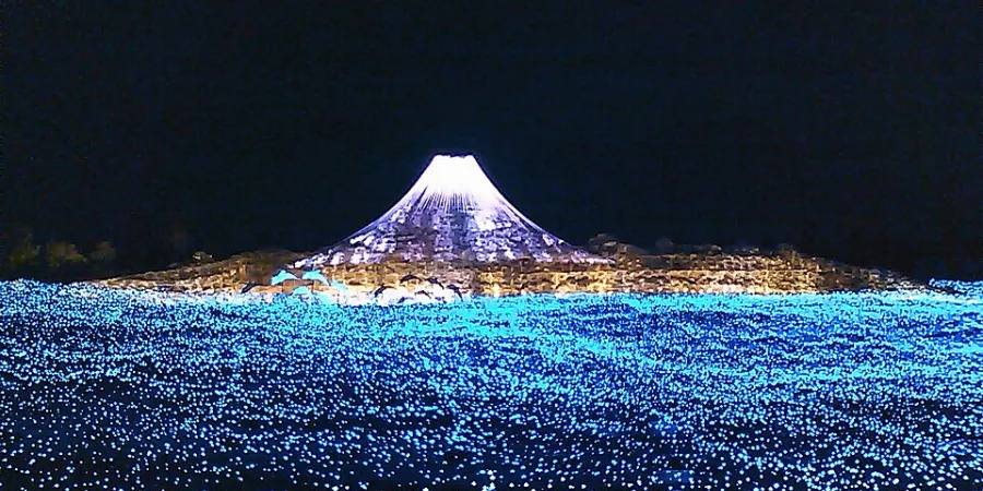 Nabana no Sato winter illumination in Mie, Japan, with Mount Fuji recreated in white and violet lights above a vast field of blue LED lights at night