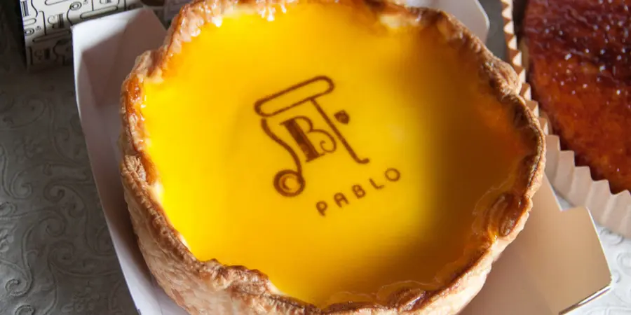 A cheesy egg tart with Pablo Cheesecake logo on it