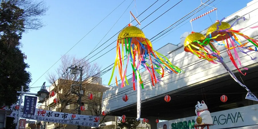 Paper decorations with coloured streamers and a lucky cat figure hanging over Boro-ichi Street in Setagaya, Tokyo, with lanterns and a Boro-ichi banner