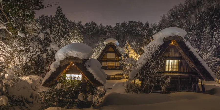 Snow-covered traditional gassho-zukuri houses illuminated at night during winter in Shirakawa-go, Japan