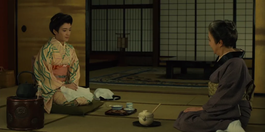 Two women in traditional Japanese clothing with a tea set in between
