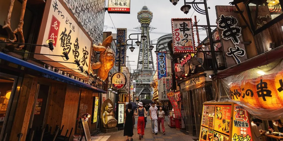 Bustling Shin Umeda Shokudogai dining alley in Osaka, Japan, with illuminated Japanese restaurant signs and small local eateries packed along a narrow alley