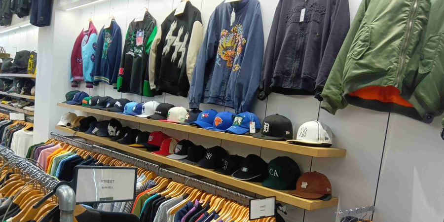 Jackets hang on the wall, while caps are displayed on shelves and clothes hang on racks in the shop, 2nd Street.