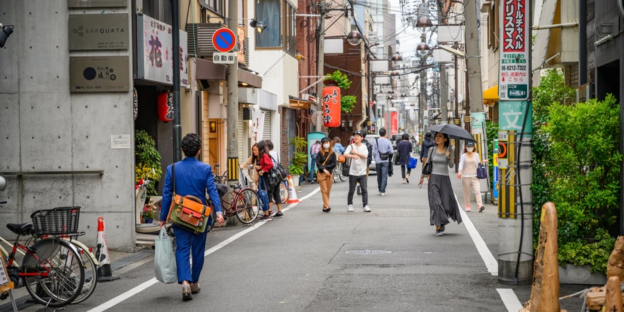 A street in Amemura with people walking, there is a man wearing a noticeable blue suit at the forefront.
