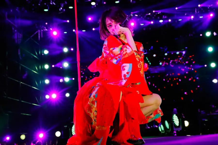 LiSA wearing modified traditional Japanese clothes, posing on-stage