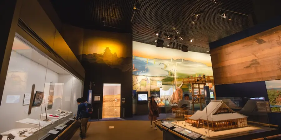 Interior of Osaka Castle Museum, with historical exhibits, large painted screens, and a scale model of the castle displayed under gallery lighting