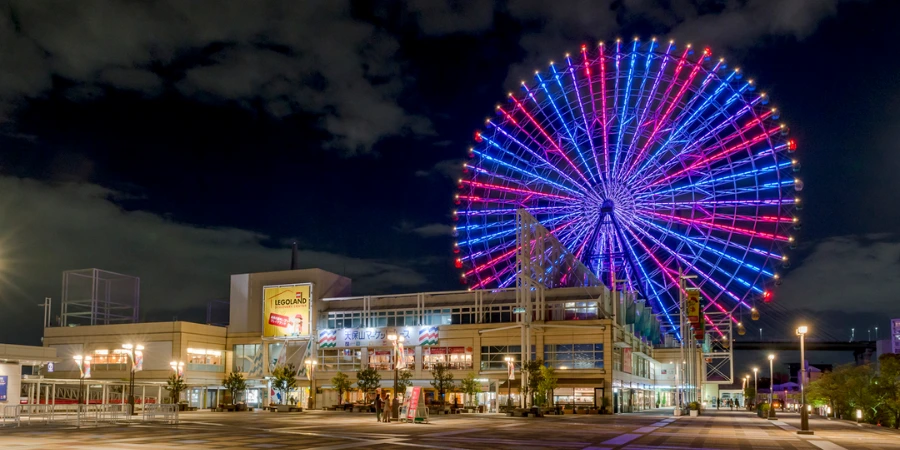 Tempozan Ferris Wheel illuminated in red and blue at night above Tempozan Harbor Village, with the waterfront plaza and shops below
