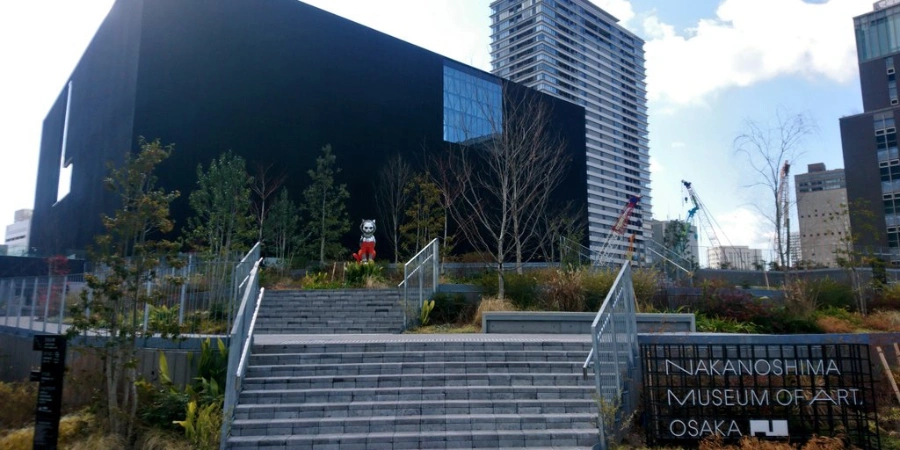Sleek, modern riverside facade of Nakanoshima Museum of Art, featuring layered glass panels and geometric black volumes.