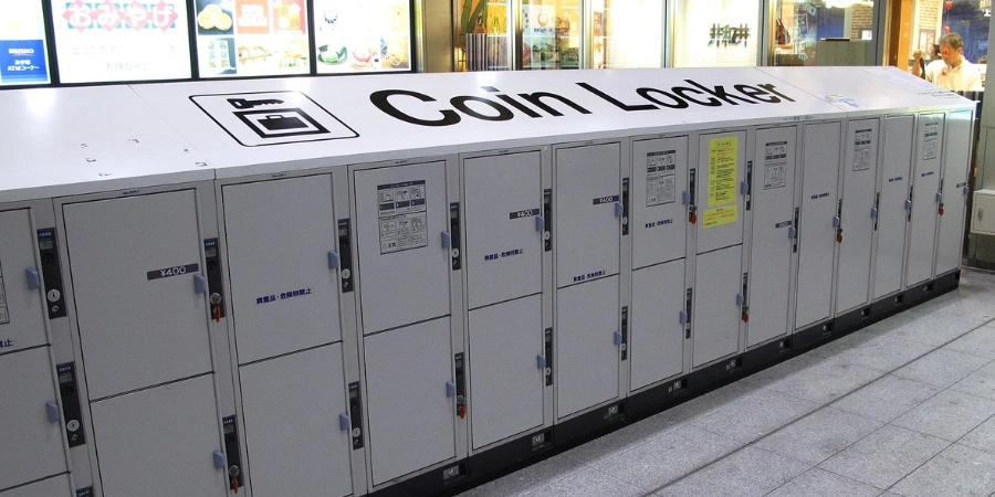 Rows of colorful coin-operated lockers inside Osaka Station, perfect for luggage storage, with digital payment panels and traveller bags nearby.