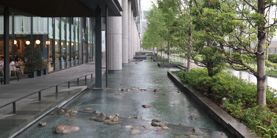 Outdoor sidewalk area at Grand Front Osaka in 2014 with artistic water feature, lush landscaping, and glass building facades creating a serene urban plaza.