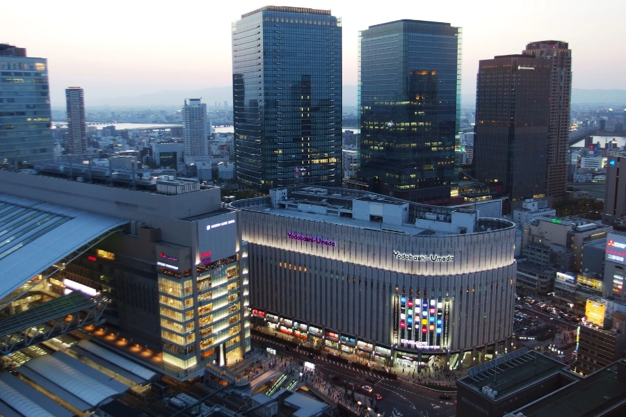 Aerial view from April 2015 showing Grand Front Osaka's modern towers alongside Yodobashi Umeda department store in Osaka's Umeda district, with urban skyline and rail lines below.