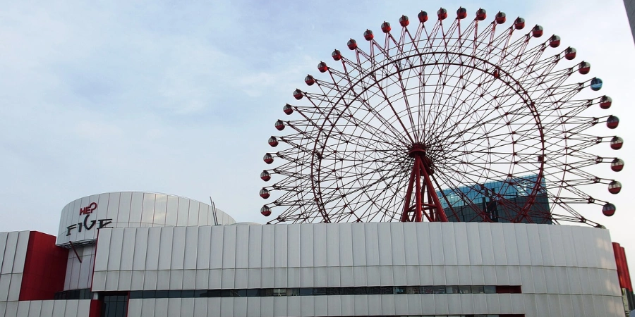 Iconic red Ferris wheel atop HEP FIVE shopping mall in Umeda, glowing against evening sky with surrounding neon lights and urban energy.