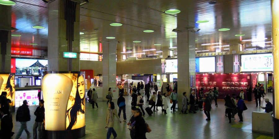 Busy underground shopping arcade at Hankyu Umeda Station's Sanbangai, with storefronts, escalators, and pedestrians in a modern Japanese mall setting.