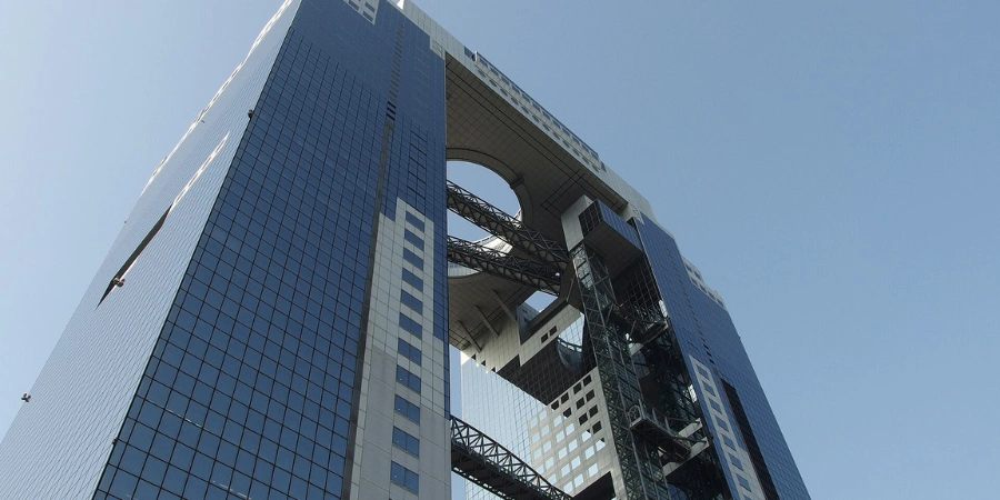 Iconic Umeda Sky Building twin towers connected by circular sky garden observatory, viewed against Osaka skyline with surrounding high-rises.