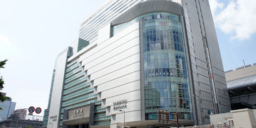 Multi-story JR Osaka Terminal Building exterior, showcasing layered architecture, signage, and connection to station platforms and urban Umeda.