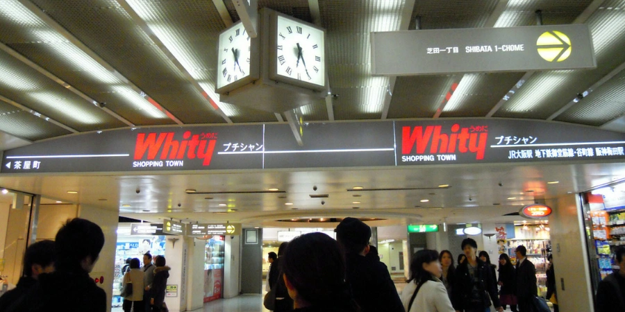 Interior of Whity Umeda underground shopping mall featuring bright atrium, escalators, shops, and crowds in central Osaka's Umeda area.