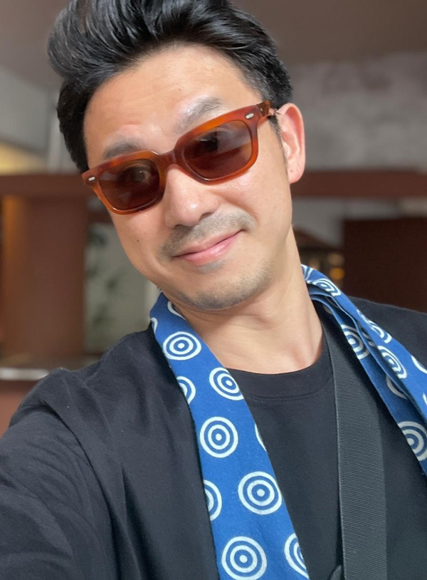 Yoshi Takagi, founder of ZONE PRESS and former MONOCLE Design Director, posing indoors, wearing sunglasses.
