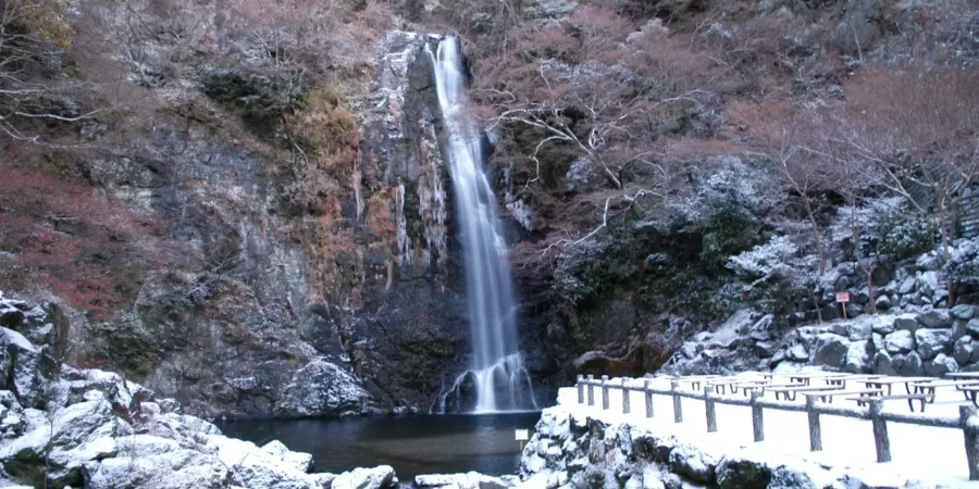 Frozen Minoo Park waterfall in winter with snow-covered rocks and a scenic forest trail in Osaka, Japan