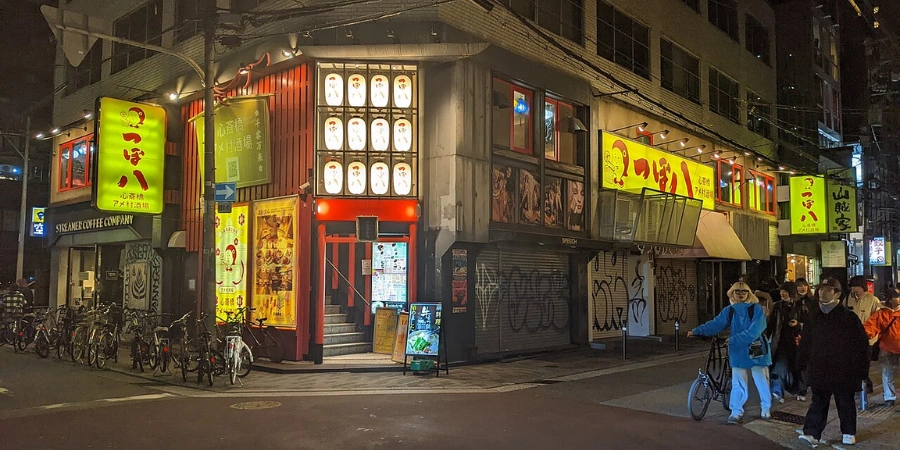 Night street view of Amerikamura in Osaka with neon signs, restaurants, and pedestrians in the entertainment district