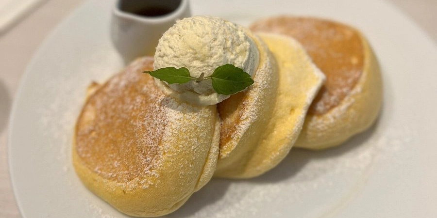 Fluffy Japanese soufflé pancakes from A Happy Pancake café in Osaka topped with whipped butter and powdered sugar
