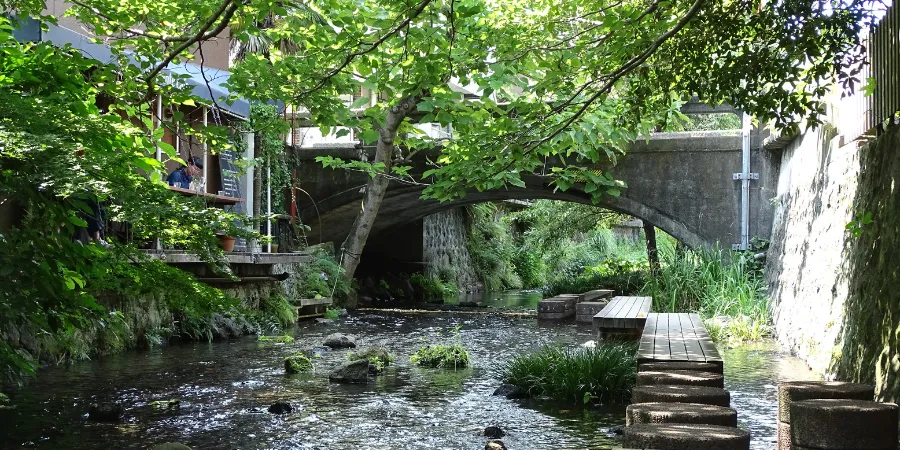 Scenic Mishima waterway with stone paths, greenery, and small bridge in Shizuoka, Japan