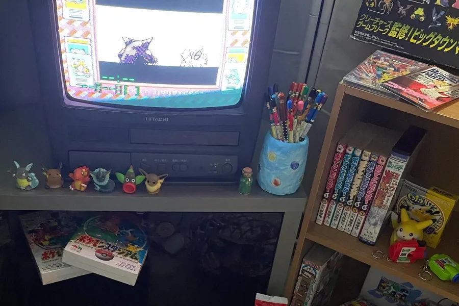 Heisei retro gaming collection featuring a vintage CRT television, Pokémon collectibles, manga, retro video games and nostalgic Japanese pop culture memorabilia.