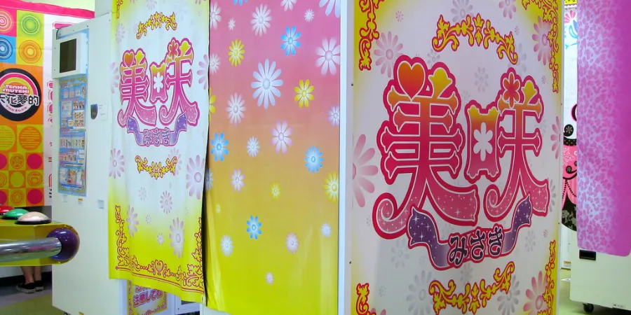 Colourful Japanese purikura photo booth machines decorated with floral graphics inside an arcade, popular for kawaii sticker photo experiences.