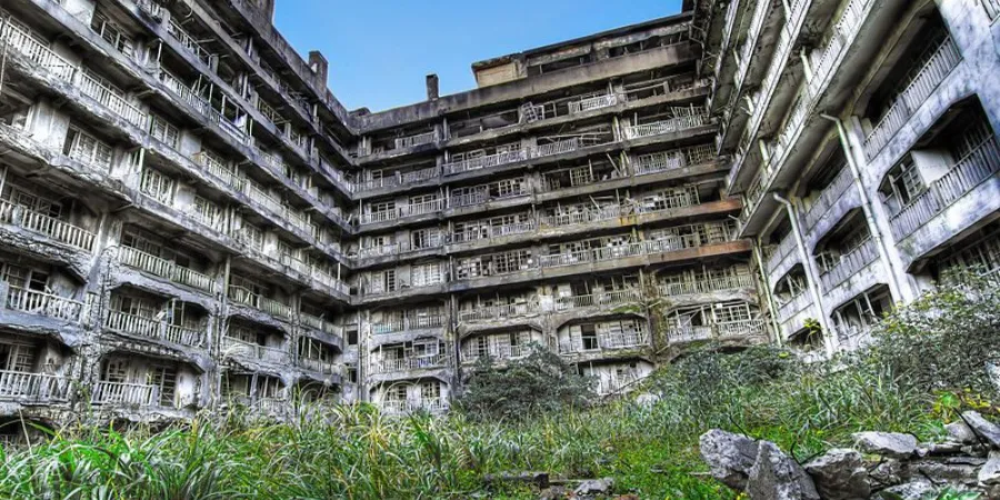 Overgrown ruins of abandoned concrete apartment buildings on Hashima Island, also known as Gunkanjima or Battleship Island.