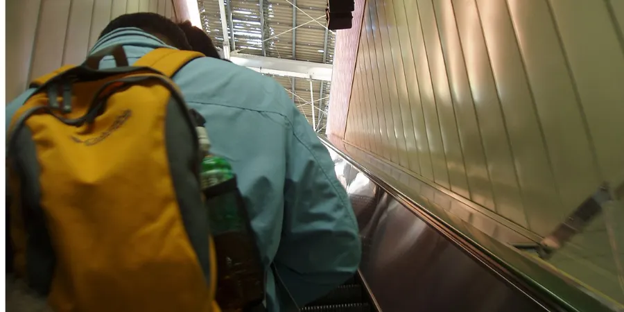 Traveller with a backpack riding an escalator at Fukushima Station, showing public transport and escalator etiquette in Japan.