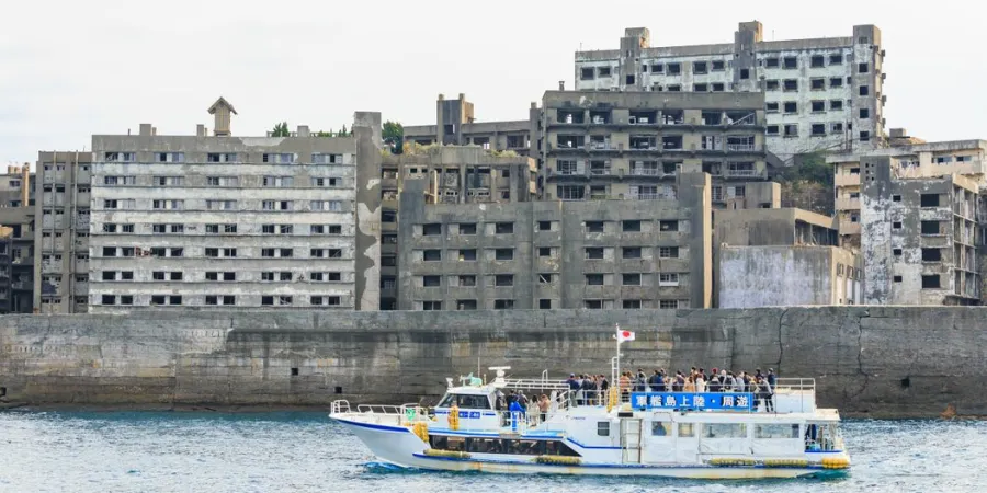 Tour boat passing the abandoned concrete buildings of Hashima Island, a former coal mining site near Nagasaki.