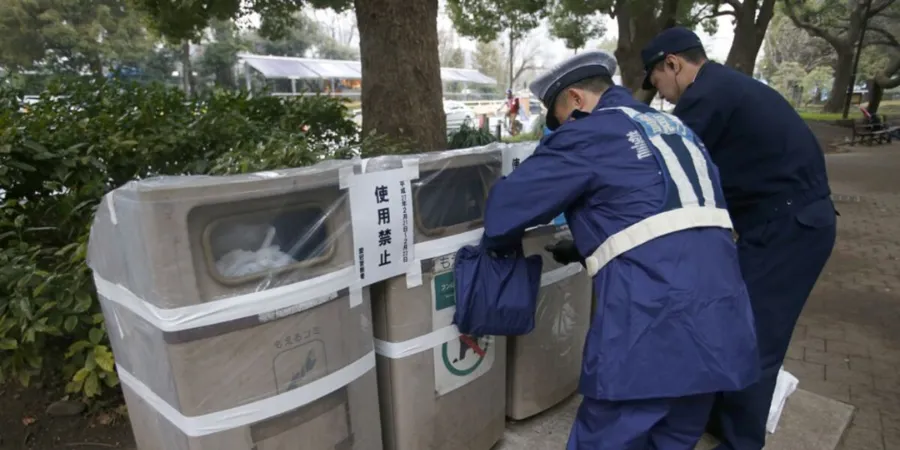 Police officers sealing off public rubbish bins in a Japanese park, highlighting Japan’s public bin rules, waste disposal etiquette, and temporary bin restrictions.