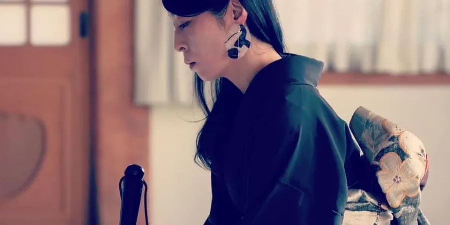 Setsuhi Shiraishi in a black kimono performing a live ink art piece during a traditional Japanese cultural performance.