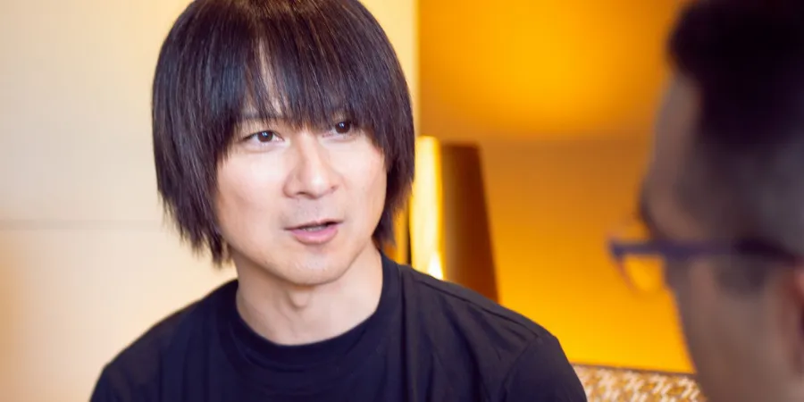 Yasunori Mitsuda speaking during an interview in a warmly lit room, ideal for articles about Square Enix music and game soundtracks.
