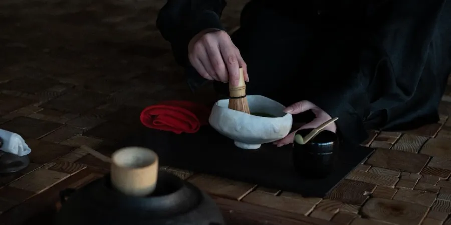 Traditional Japanese tea ceremony with matcha being whisked in a ceramic tea bowl using a bamboo whisk, showcasing authentic Japanese tea culture and ceremonial preparation.