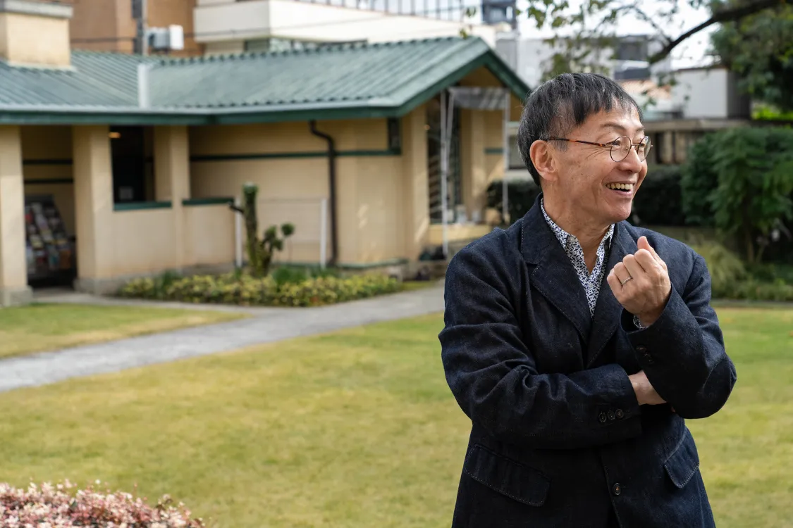 Japanese playwright and theatre director Hideki Noda smiling outdoors during an interview.