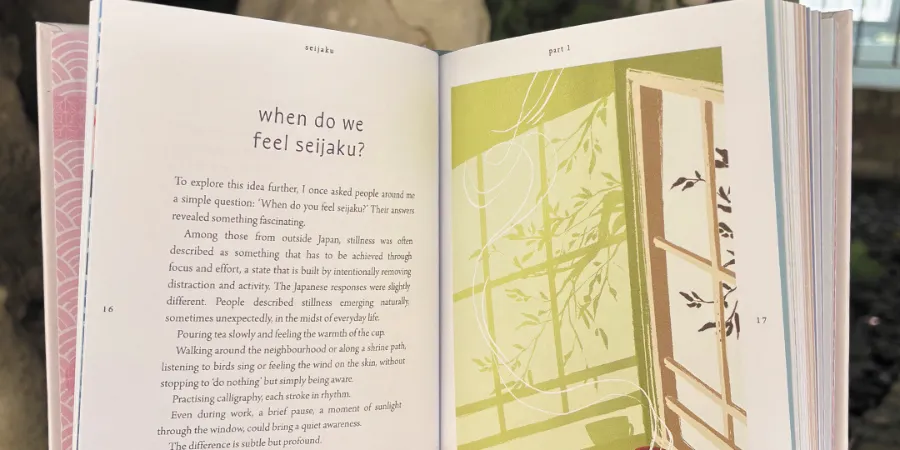Open pages from Seijaku: The Japanese Secret to Finding Stillness explaining the meaning of seijaku, featuring an illustrated Japanese window scene inspired by Zen, mindfulness, and quiet reflection.