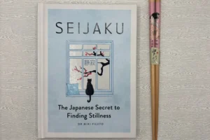 Hardcover edition of Seijaku: The Japanese Secret to Finding Stillness by Dr. Miki Fujito displayed beside traditional Japanese chopsticks, highlighting Japanese culture, mindfulness, and Zen-inspired living.