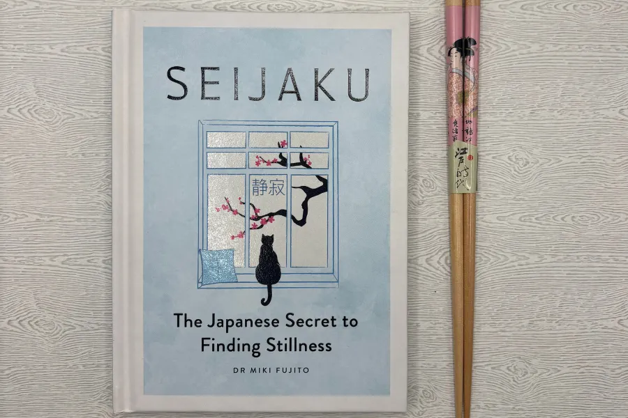 Hardcover edition of Seijaku: The Japanese Secret to Finding Stillness by Dr. Miki Fujito displayed beside traditional Japanese chopsticks, highlighting Japanese culture, mindfulness, and Zen-inspired living.